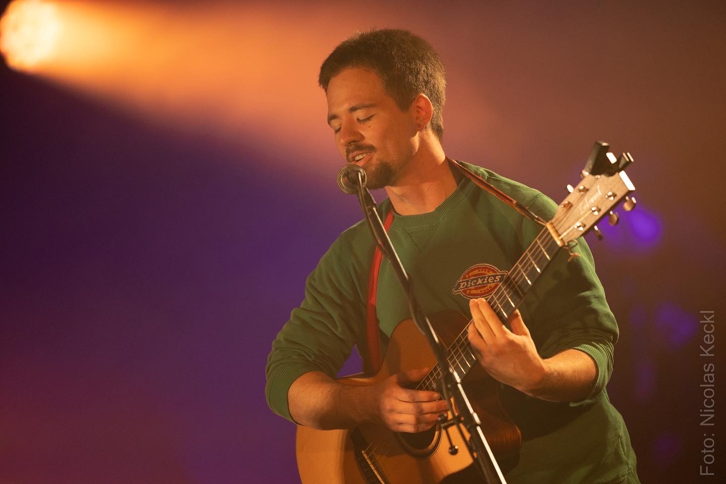 flowoflife (Florian Walchshäusl) live auf der Bühne mit Akustikgitarre und Mikrofon